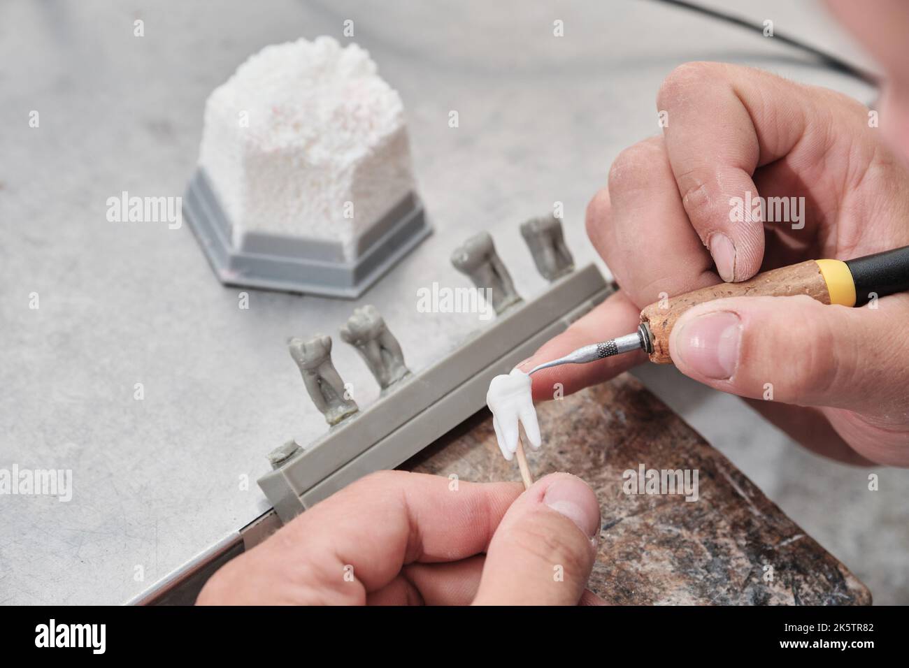 Dentista dentista uomo che lavora con dentiere nel suo laboratorio con cera, primo piano. Tecnico dentale modellante corone di denti con cera calda. Foto Stock