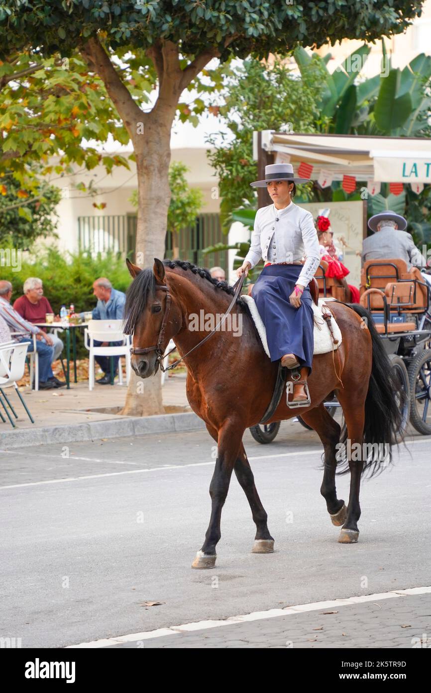 Donna spagnola vestita in costume tradizionale, equitazione durante la Feria, di Fuengirola, Andalusia, Spagna. Foto Stock