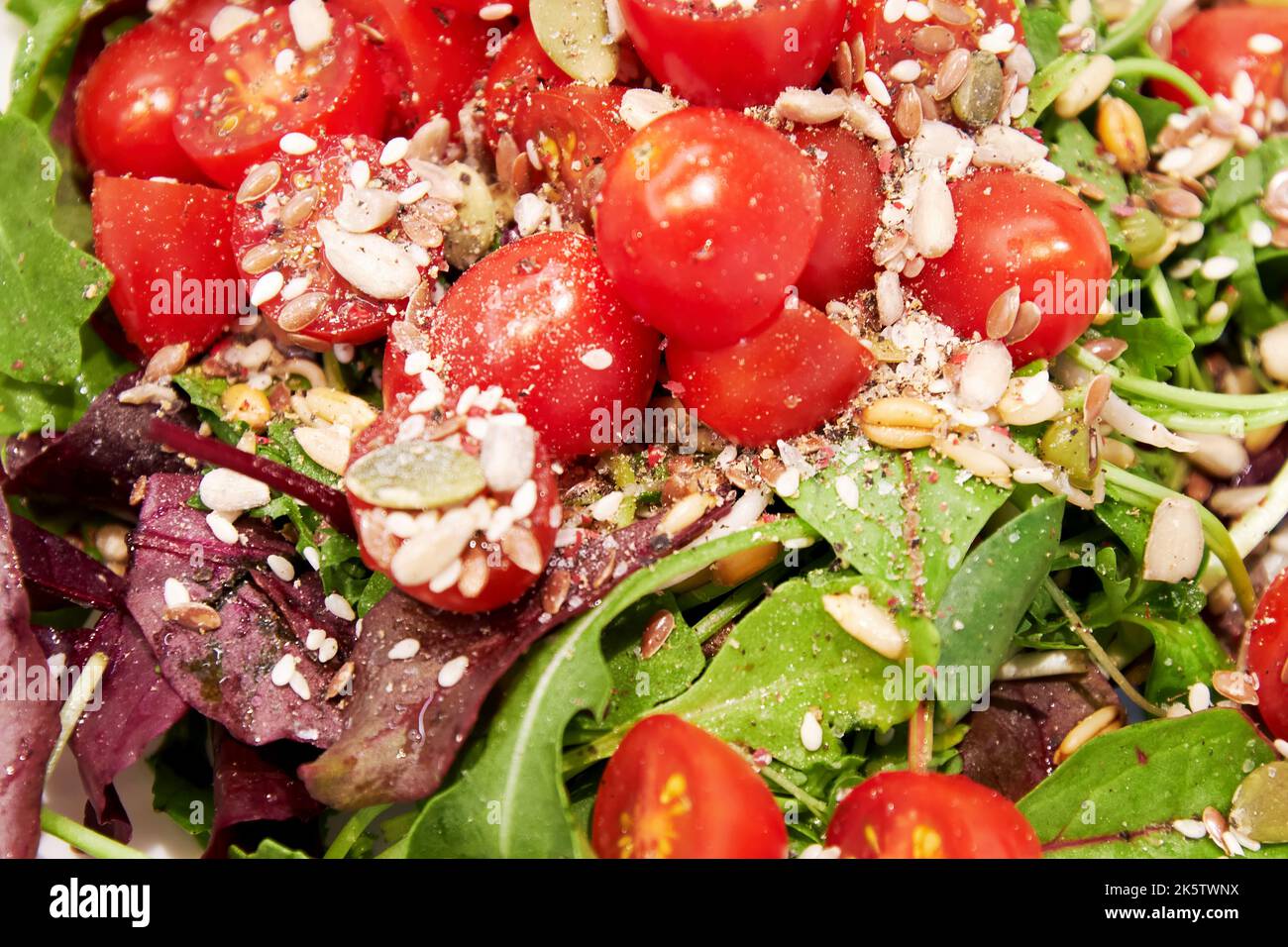 Insalata di verdure con pomodori, lattuga verde, semi e olio. Texture di fondo del cibo Foto Stock