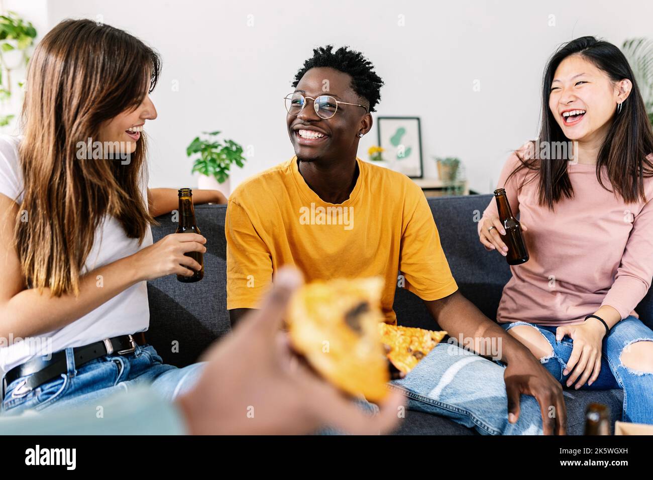 Un giovane gruppo di amici più diversi che si gustano la pizza insieme alla festa di casa Foto Stock