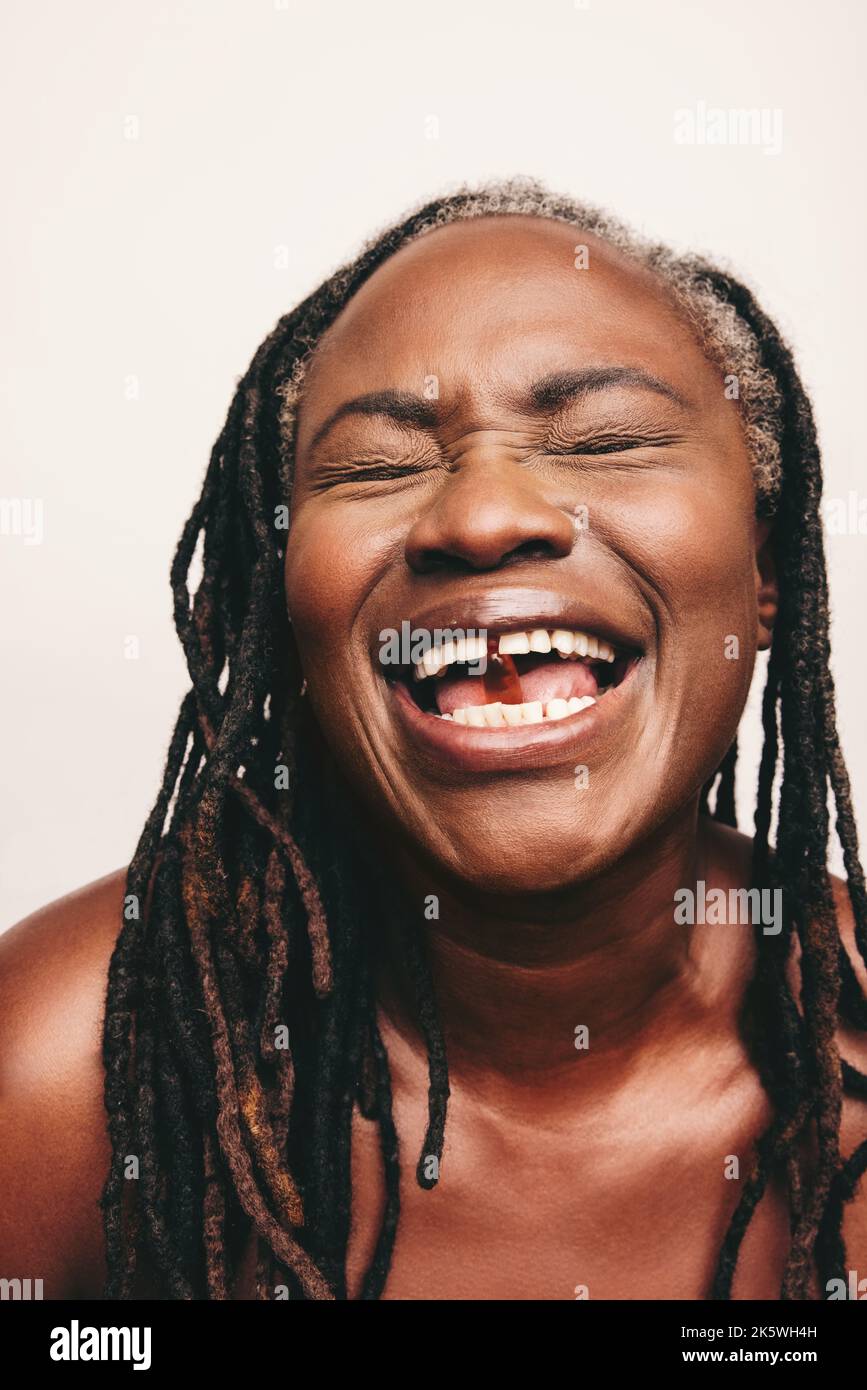 Donna spensierata sorridente felicemente con una capsula di acidi grassi Omega 3 in bocca. Donna matura con greggi usando i supplementi nutrizionali come parte Foto Stock