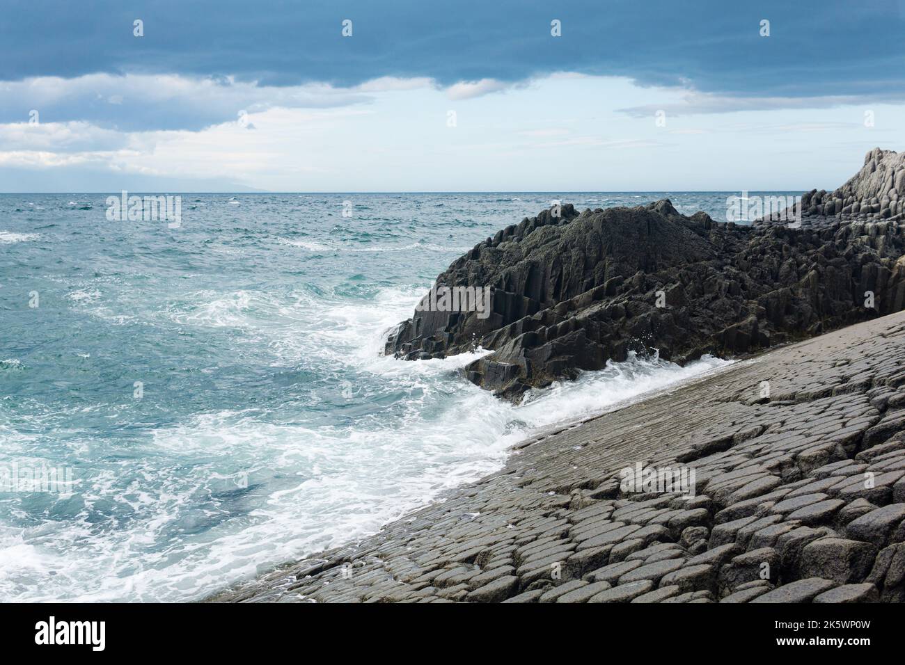 Litorale roccioso formato da basalto colonnare contro il surf, paesaggio costiero delle isole Kuril Foto Stock