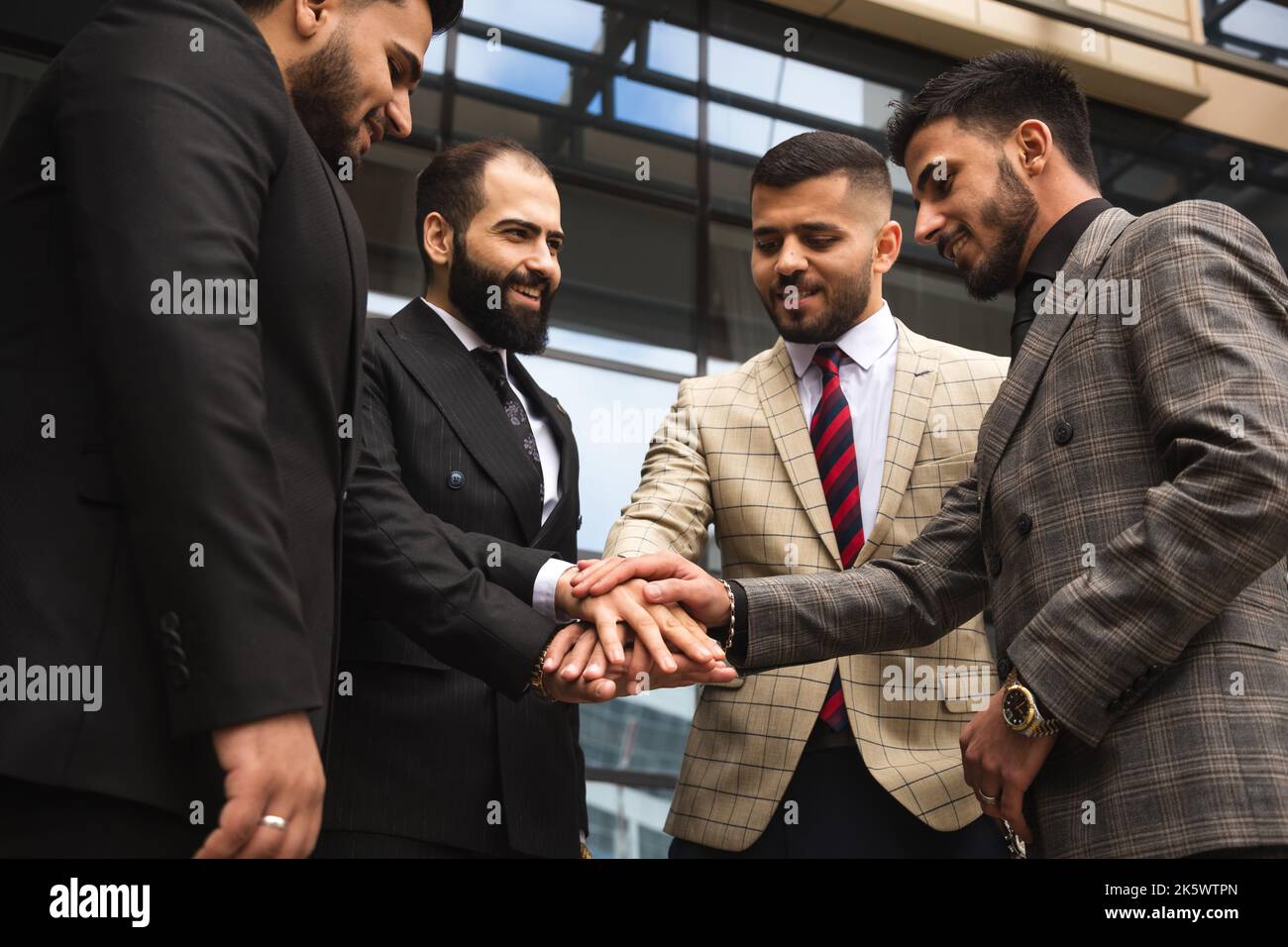 Team internazionale di imprese di persone di successo che celebrano la vittoria. Gli uomini in tute in una riunione aziendale gioiscono per i risultati della loro azienda Foto Stock