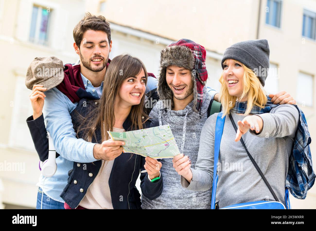 Gruppo di giovani turisti hipster amici tifosi con la mappa della città nel centro storico - concetto di stile di vita di viaggio con persone felici divertirsi insieme - Wint Foto Stock