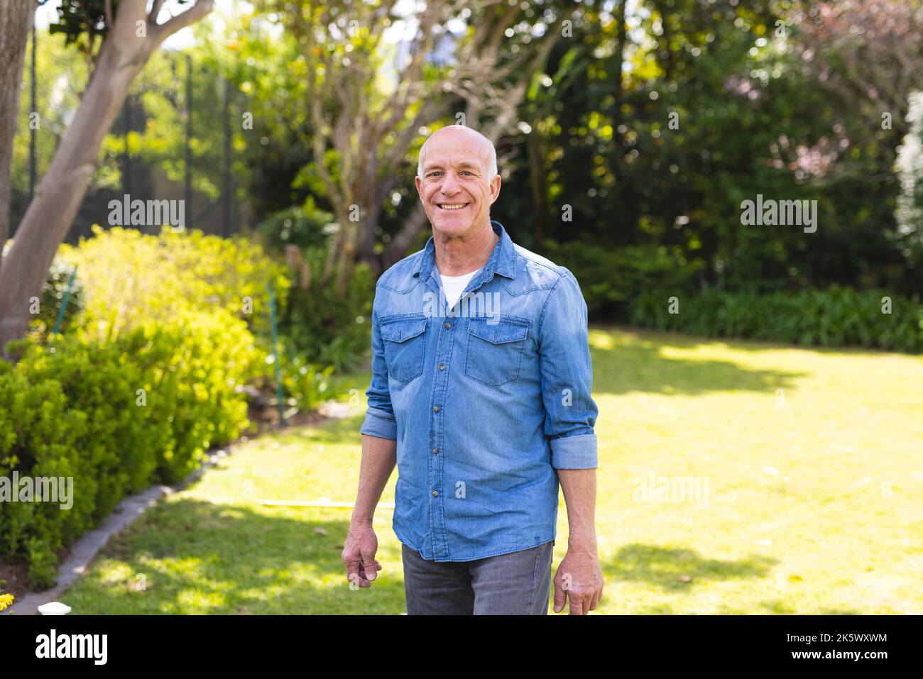 Ritratto di uomini caucasici anziani che indossano una camicia blu e che si trovano in giardino Foto Stock