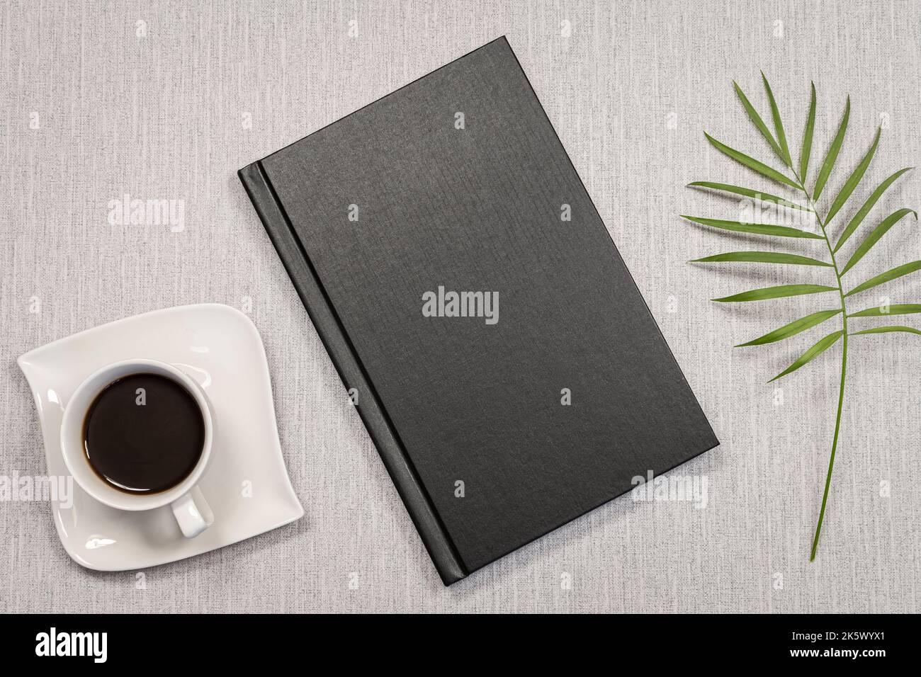 Libro nero e tazza da caffè su sfondo grigio. Foto Stock