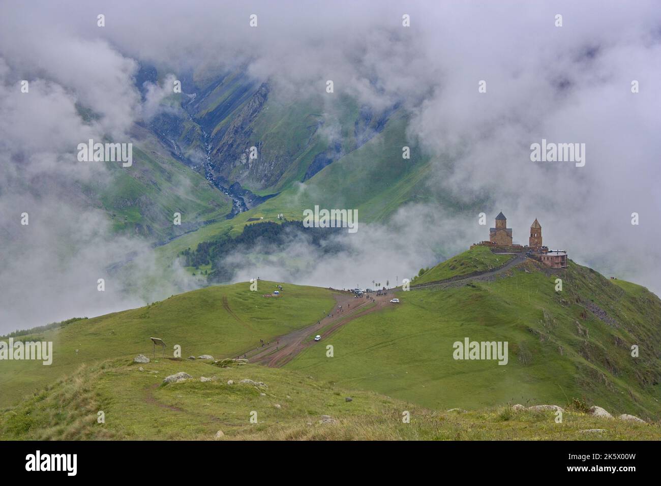 La Santa Chiesa della Trinità Gergeti nelle nuvole in Georgia, il Caucaso con montagne sullo sfondo Foto Stock