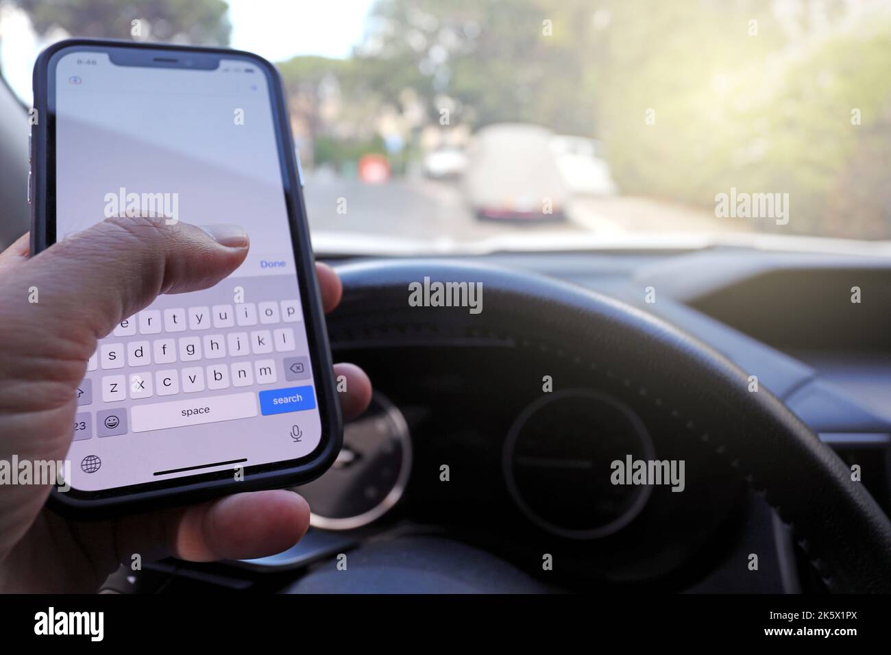 Invio di SMS durante la guida di un'auto. Scrivere e digitare il messaggio con il cellulare nel veicolo. Foto Stock