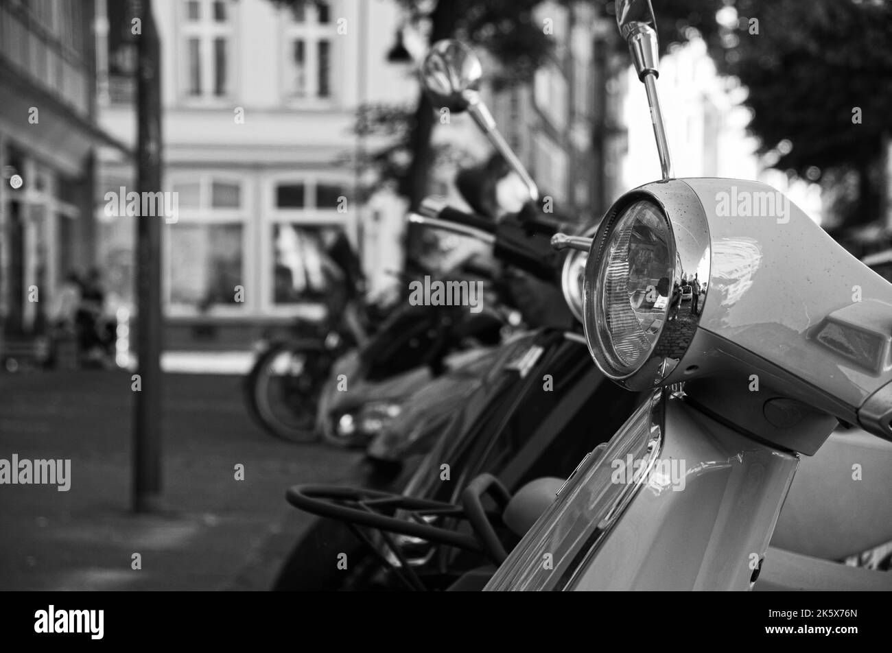 La vista parziale in scala di grigi delle motociclette parcheggiate da un marciapiede Foto Stock