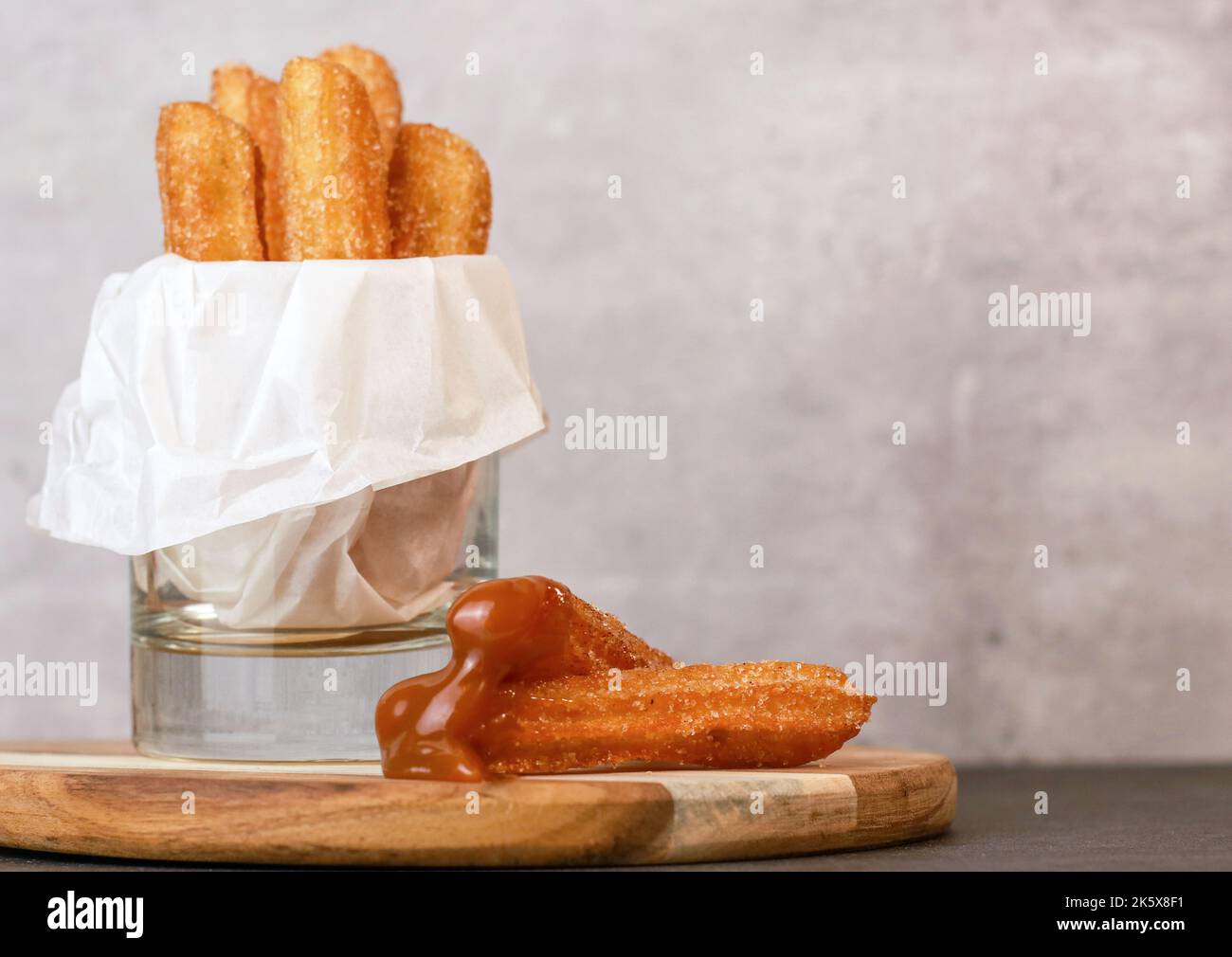 Churros con zucchero e salsa al caramello in un tavolo grigio di vetro con spazio copia Foto Stock