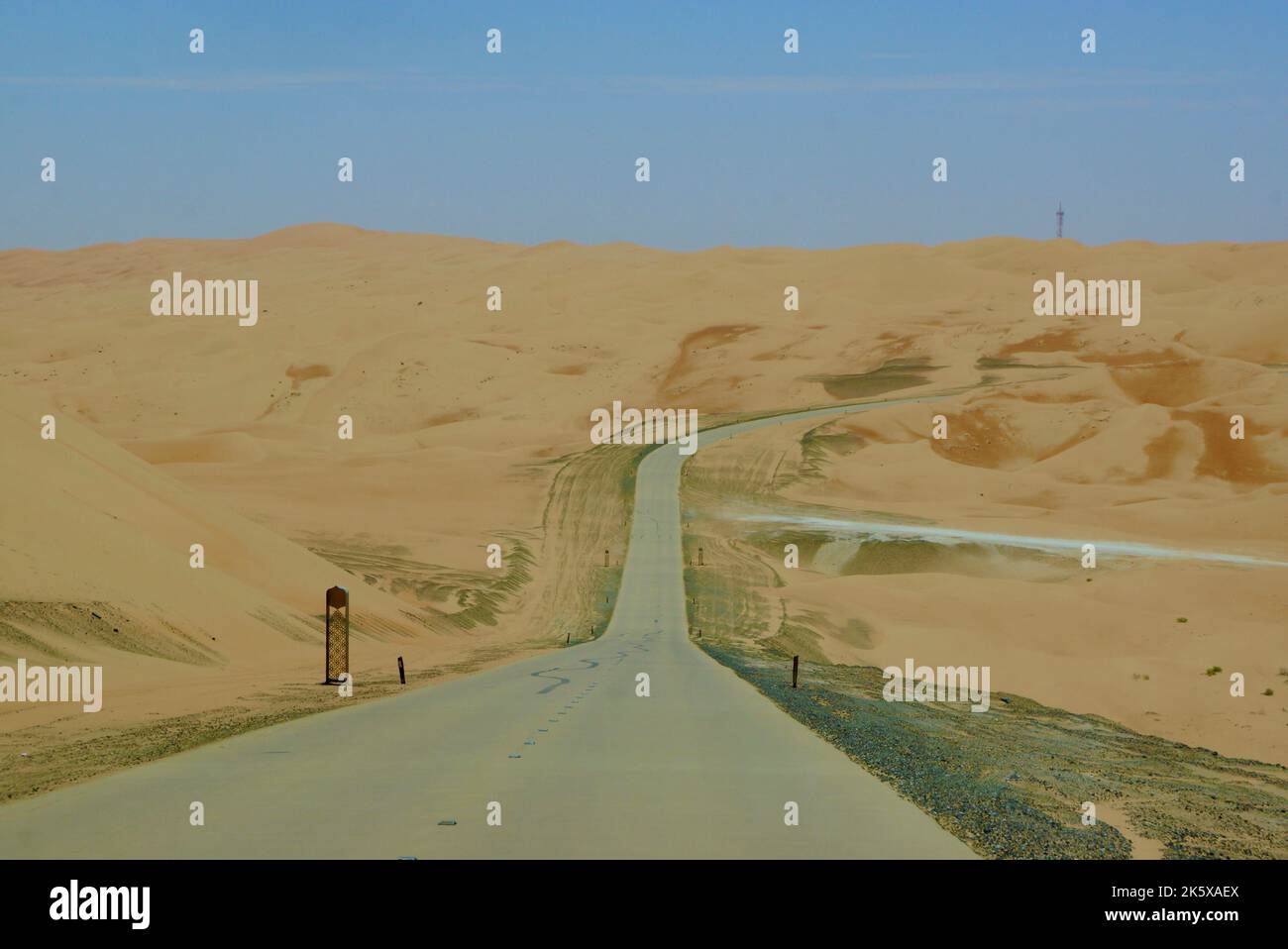Una strada che attraversa dune di sabbia sulla strada per il resort nel deserto di Qasr al Sarab da Anantara ad Abu Dhabi Foto Stock
