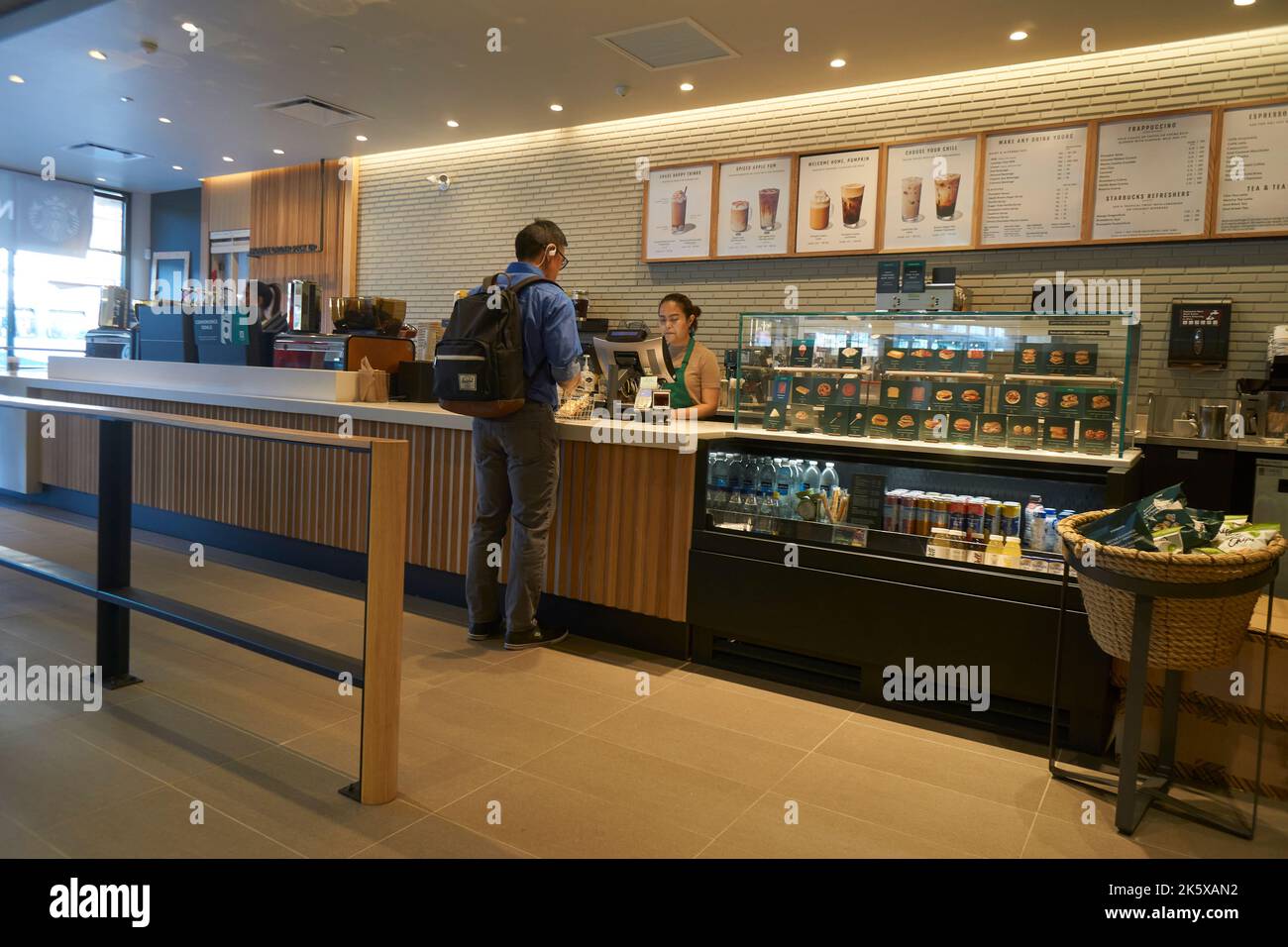 Giovane uomo che effettua un ordine al banco di un caffè Starbucks a Vancouver, BC, Canada Foto Stock