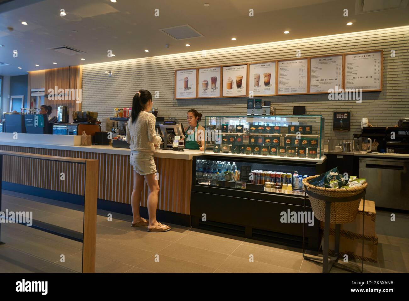 Giovane donna che effettua un ordine al banco di un caffè Starbucks a Vancouver, BC, Canada Foto Stock