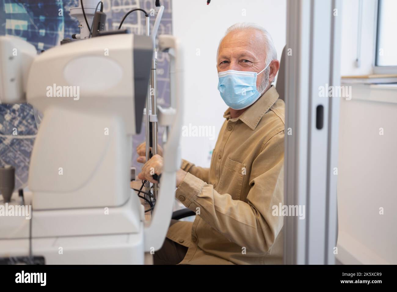 Uomo anziano che indossa una maschera che tiene in mano le apparecchiature cliniche Foto Stock