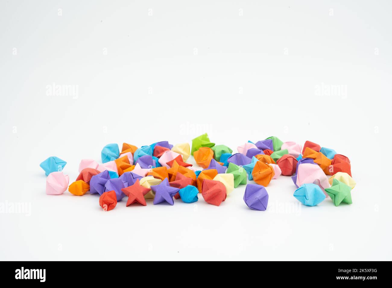 Piccole stelle di origami sparse di vari colori Foto Stock