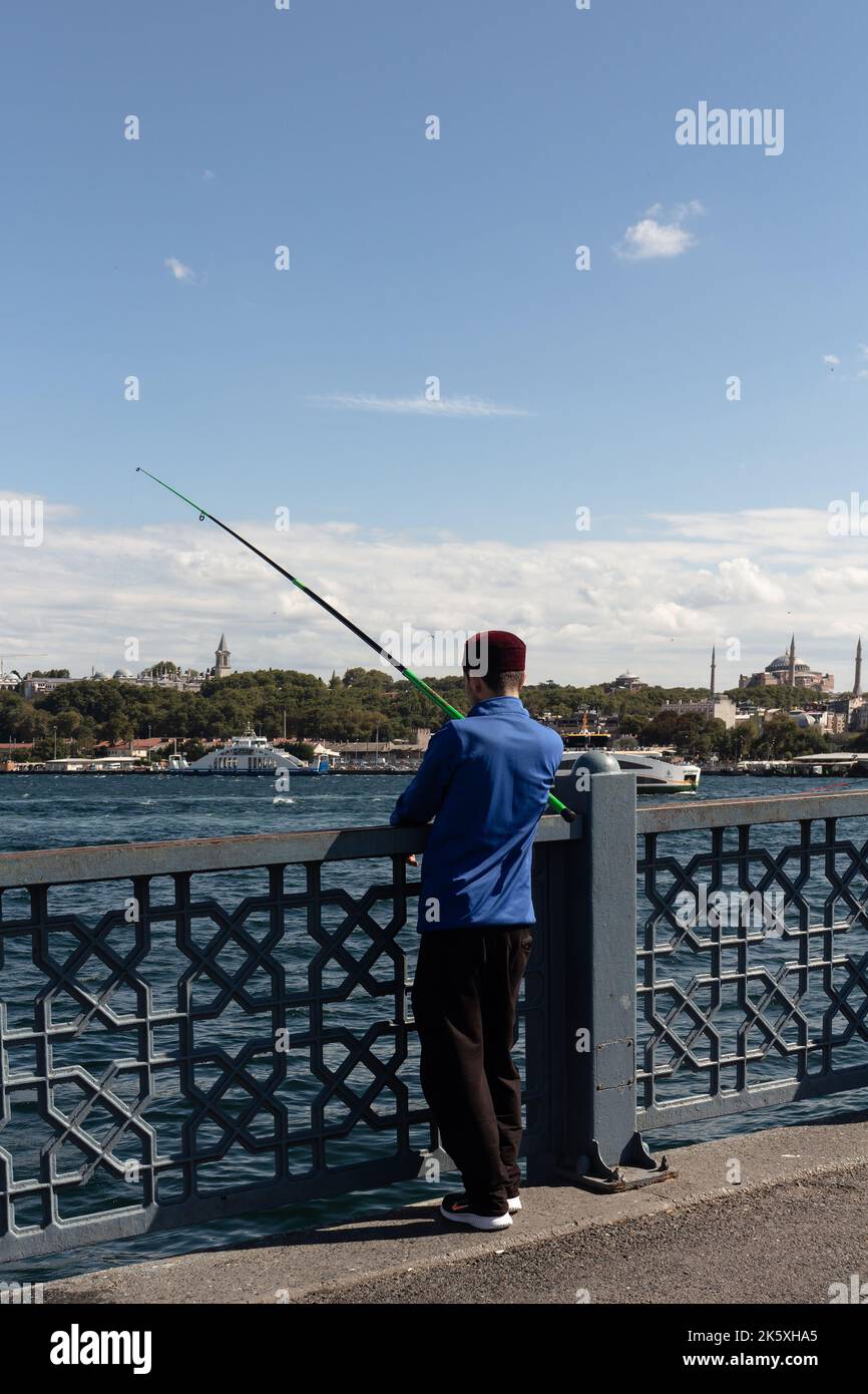 Vista dell'irriconoscibile pescatore sul ponte Galata di Istanbul. L'immagine riflette lo stile di vita e la cultura della gente locale è una giornata estiva di sole. Foto Stock
