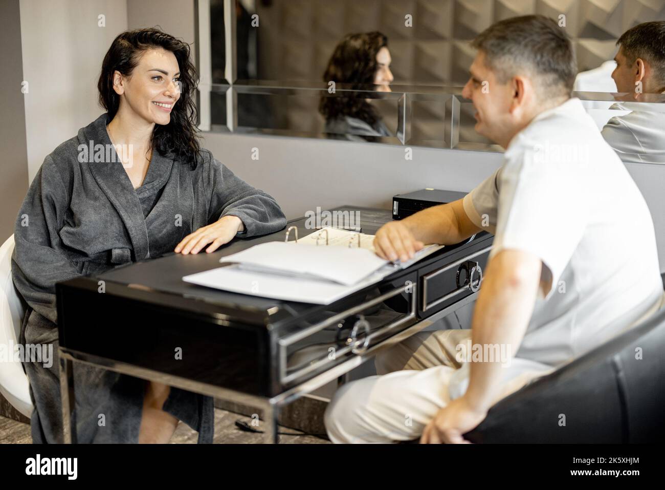 Donna in accappatoio su appuntamento con terapista senior Foto Stock