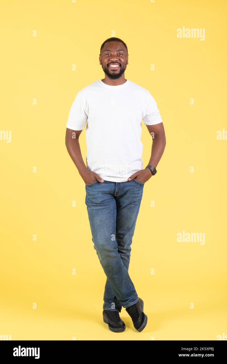 Bel maschio Nero sorridente in piedi su sfondo giallo Studio Foto Stock