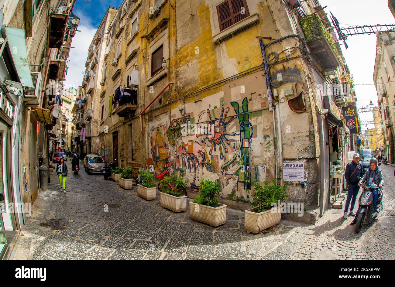 04 2022 aprile - Napoli Italia - la strada affollata una mattina con un sacco di scooter e persone a piedi per lavorare accanto a vecchi edifici colorati Foto Stock