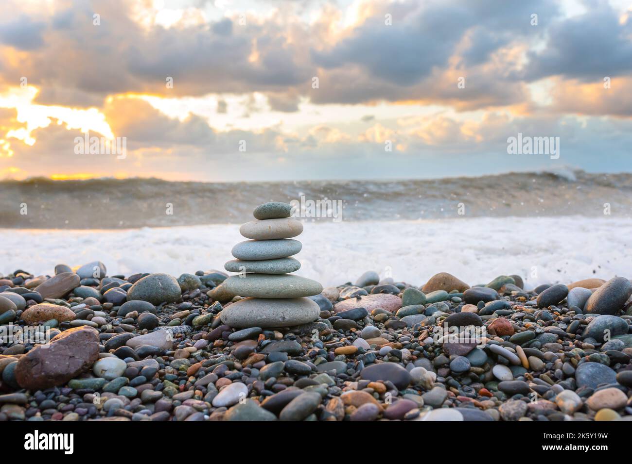 Una piramide di pietra per la meditazione che giace sulla riva del mare al tramonto Foto Stock