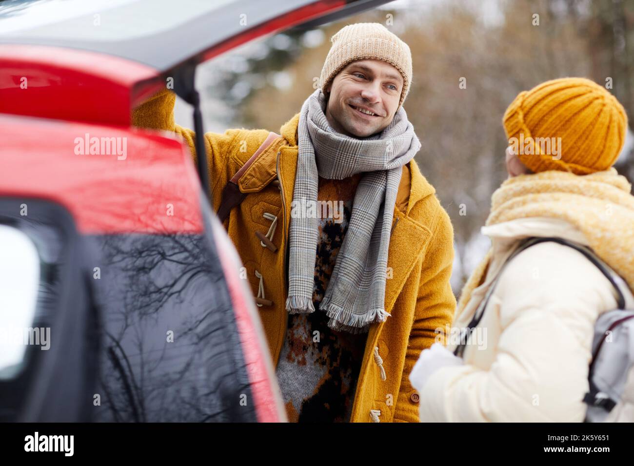 Ritratto di giovane coppia sorridente in piedi in auto in arrivo per le vacanze invernali Foto Stock
