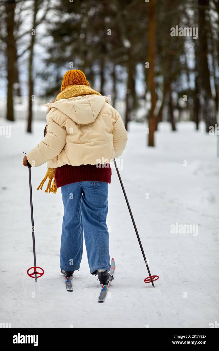 Vista sul retro della giovane donna che sciava nella foresta d'inverno e si diverse a praticare attività all'aperto Foto Stock