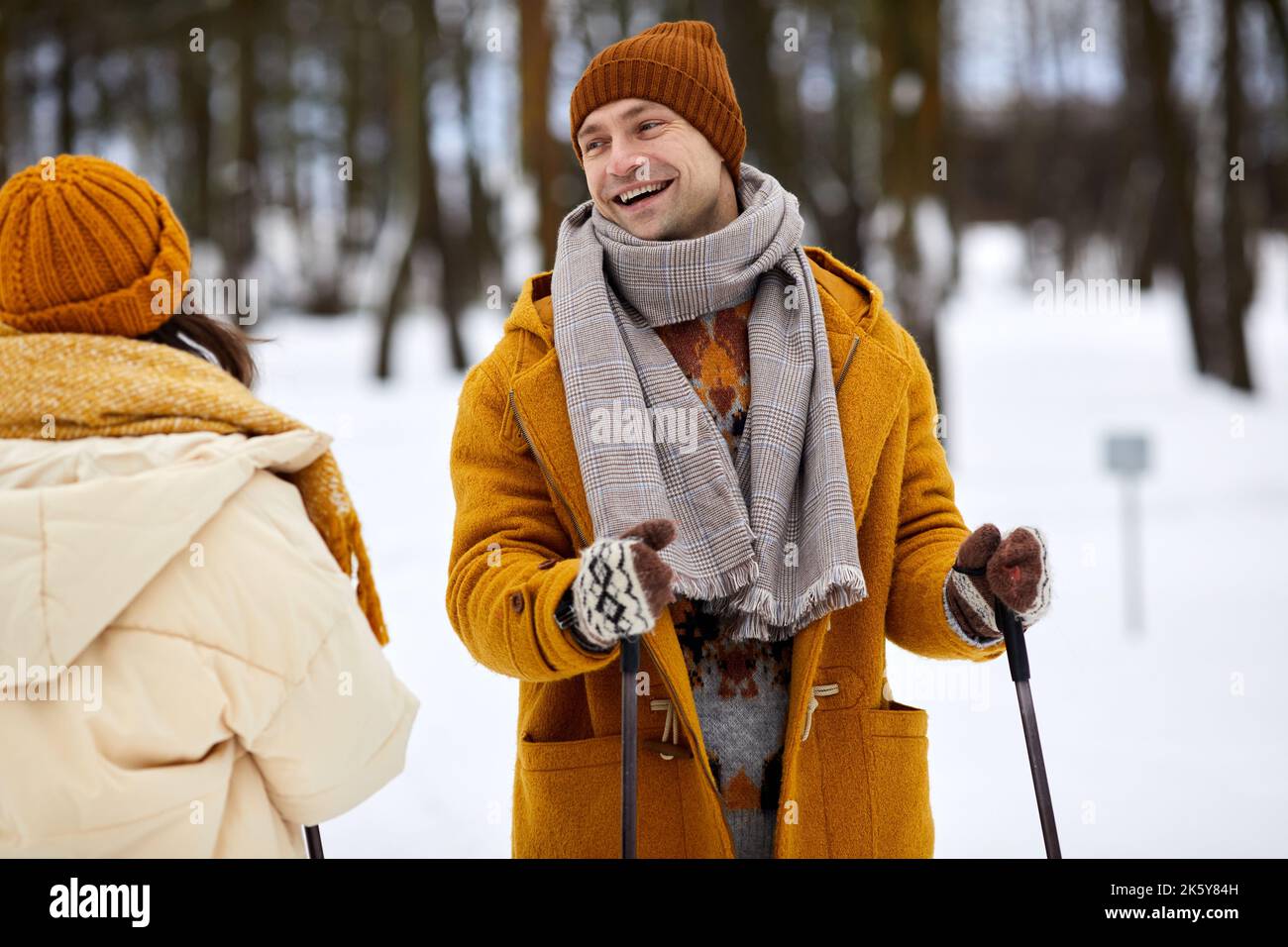 Vita in su ritratto di coppia felice sciare nella foresta d'inverno, concentrarsi su giovane uomo spensierato con bastoni da sci sorridente alla ragazza Foto Stock