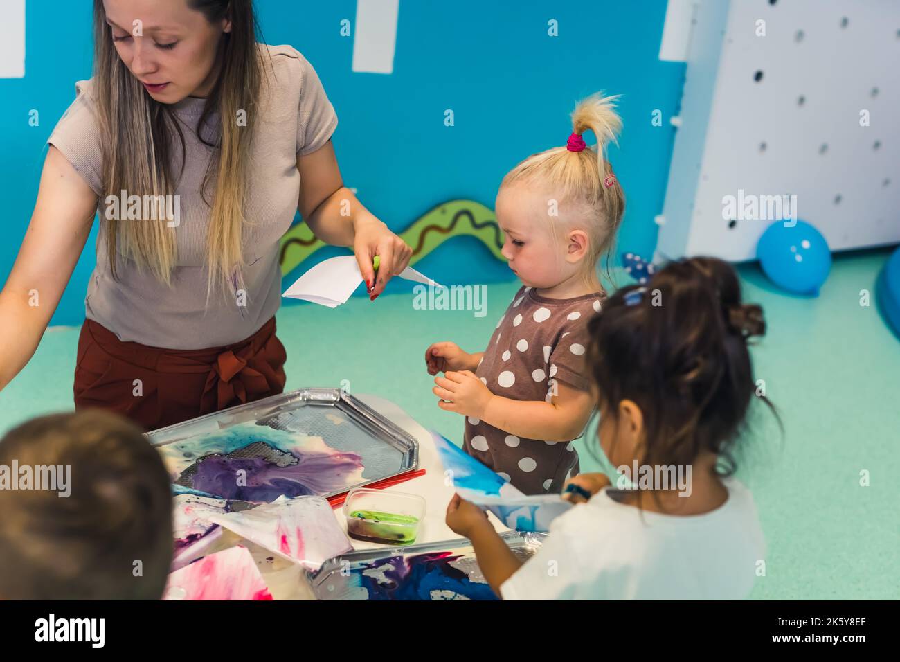 insegnante di nuove tecniche di pittura con i suoi amati figli nell'asilo. Foto di alta qualità Foto Stock