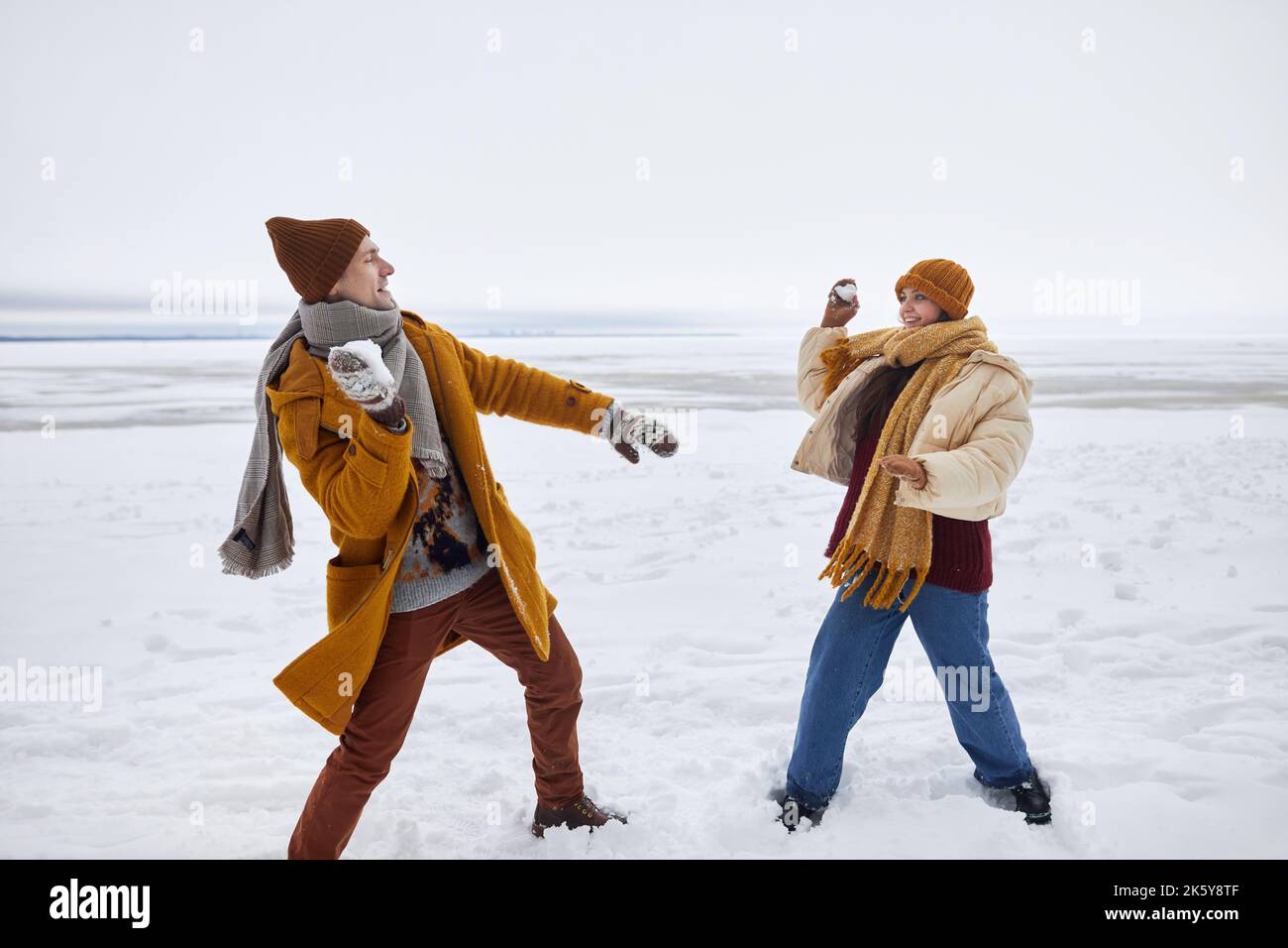 Ritratto a tutta lunghezza di coppia giocando a palla di neve lotta all'aperto in inverno, copia spazio Foto Stock