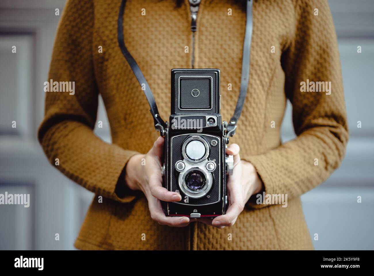 Una giovane donna tiene una telecamera retrò da 120 mm. Foto Stock