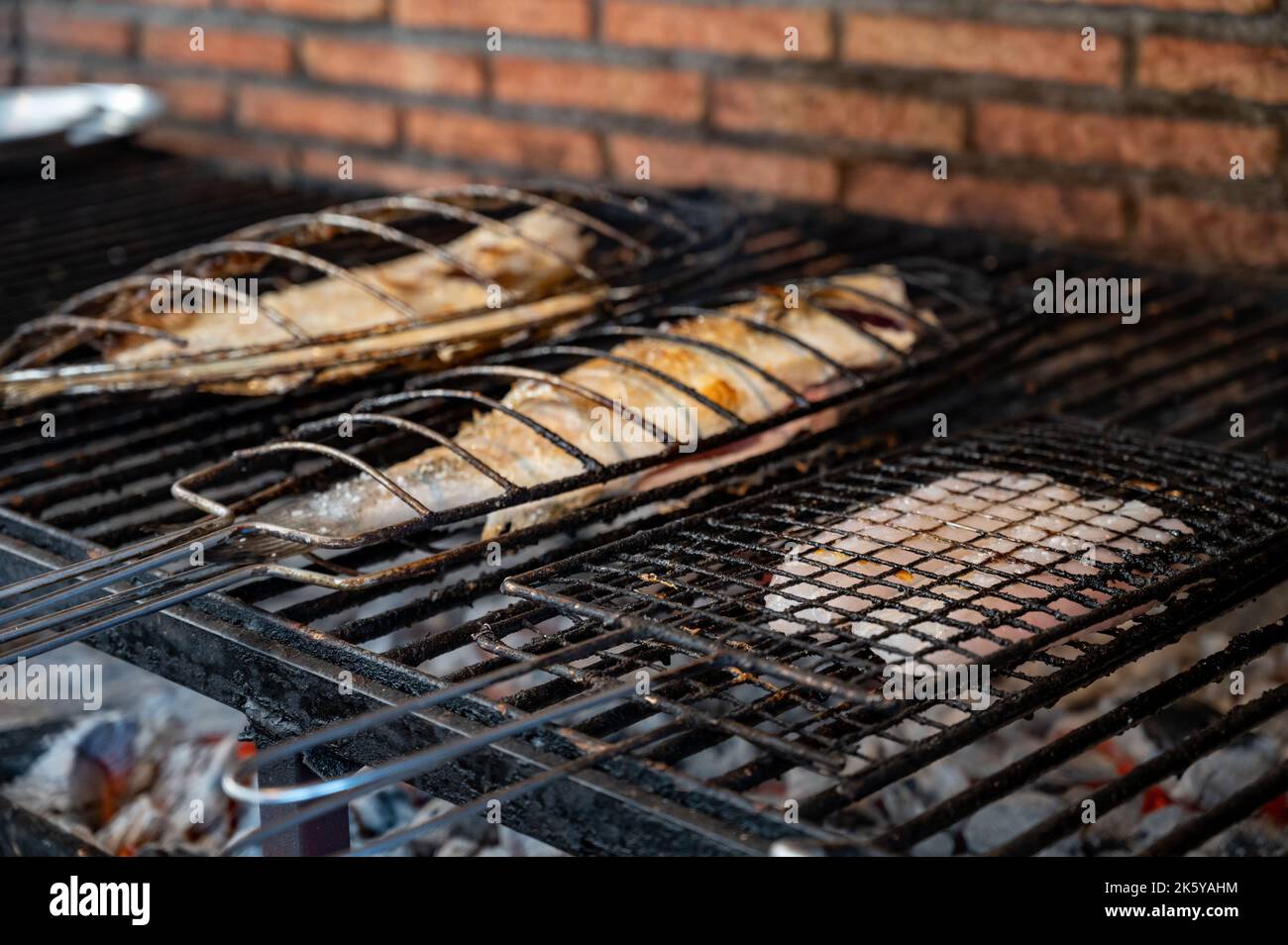 Pesce fresco grigliando su vecchio carbone parrillas pesce bianco spigola e rombo, costruire al di fuori degli edifici in piccolo villaggio di pescatori Getaria, basco Foto Stock