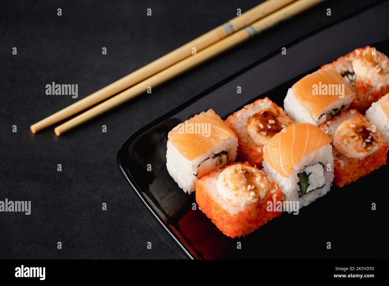 Set di sushi roll su piastra nera. Il ristorante serve piatti Giapponesi.  Famoso piatto asiatico di riso e frutti di mare e bacchette. Rotoli Uramaki  Foto stock - Alamy
