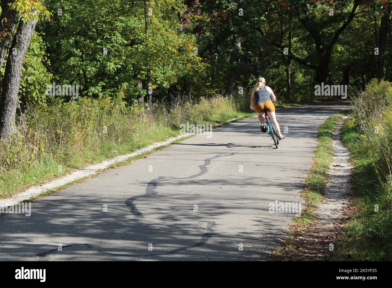 Donna che fa un salto sulla sua bicicletta sul North Branch Trail a Morton Grove, Illinois Foto Stock