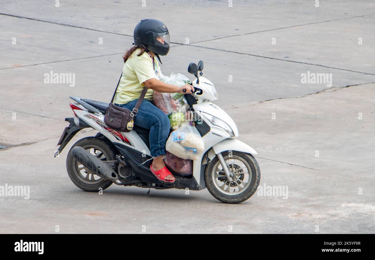 SAMUT PRAKAN, THAILANDIA, ottobre 03 2022, Una donna con la spesa in borse di plastica giro una moto Foto Stock