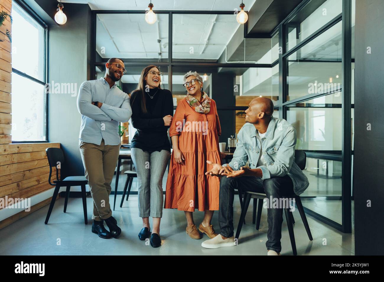 Gruppo di uomini d'affari multiculturali che ridono felicemente in una sala riunioni dell'ufficio. Colleghi aziendali di successo che lavorano insieme in un ambiente di lavoro moderno. Foto Stock