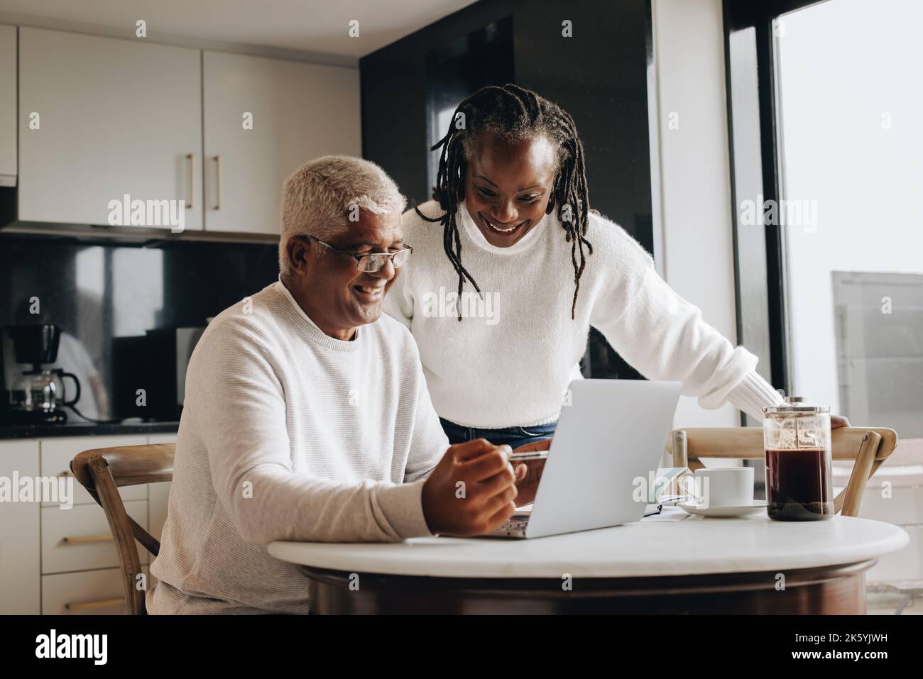 Previdenza a casa. Allegra coppia anziana sorridente felicemente mentre guardava lo schermo di un notebook. Coppia matura felice che cerca il loro pensionamento Foto Stock