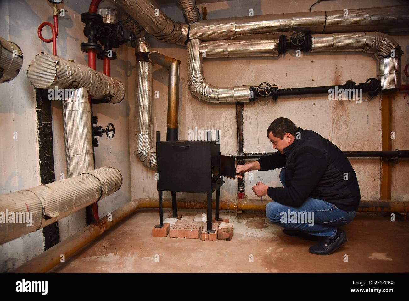 Un uomo accende una stufa di metallo nel seminterrato di una casa che serve  come un riparo bomba. In molti seminterrati di edifici residenziali a Lviv,  che servono come ripari bomba durante