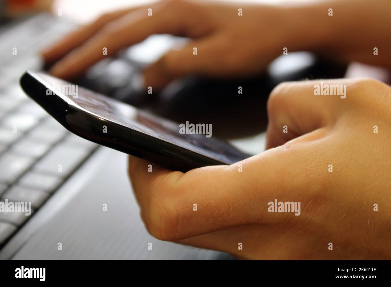 La ragazza si siede a un computer portatile e tiene uno smartphone nelle sue mani. Concetto aziendale. Shopping online Foto Stock