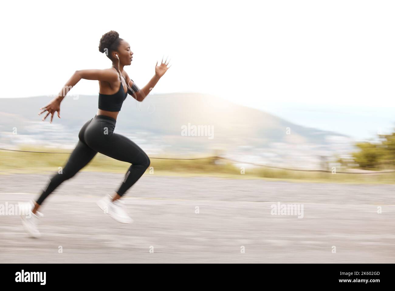 Una atleta afro-americana che cerca concentrato mentre fuori per correre per aumentare il suo cardio e la resistenza. Una giovane donna nera che corre fuori a. Foto Stock