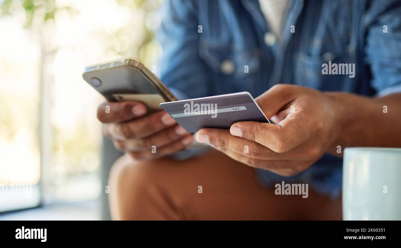 Primo piano di un bachelor utilizzando la sua carta di credito per effettuare pagamenti online. Mani di un uomo che paga per un ordine in linea. Fare acquisti online non è mai stato così facile Foto Stock