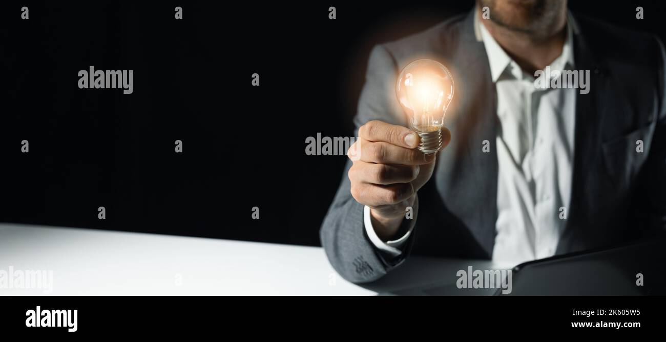 uomo d'affari che tiene a portata di mano una lampada luminosa. soluzioni aziendali, startup e nuovo concetto di idea. banner con spazio per la copia Foto Stock