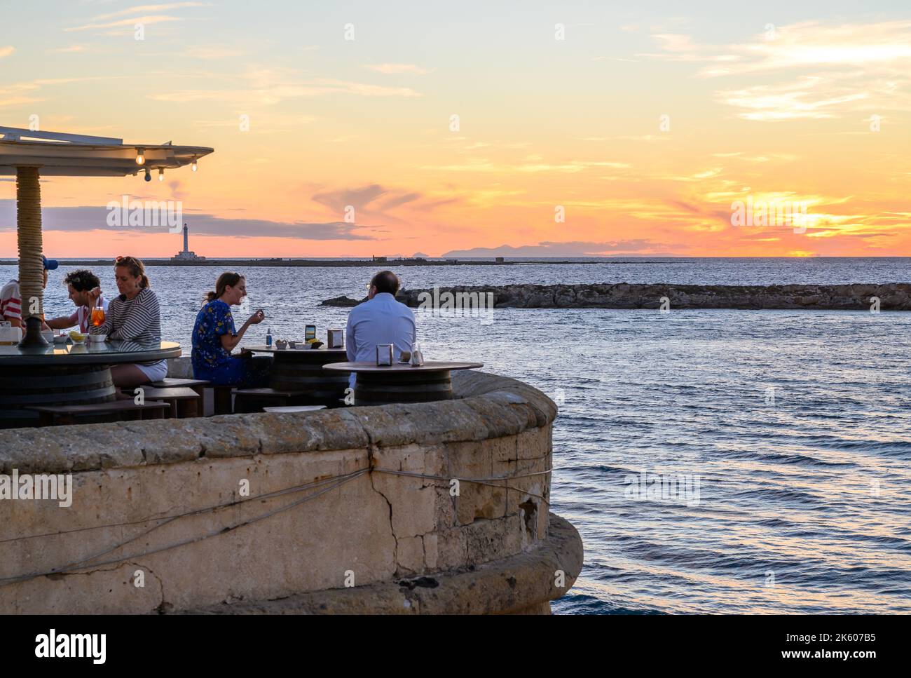 Le persone che si gustano cibo e bevande al ristorante all'aperto Buena Vista sul lungomare medievale bastione nel centro storico di Gallipoli, Puglia, Italia. Foto Stock