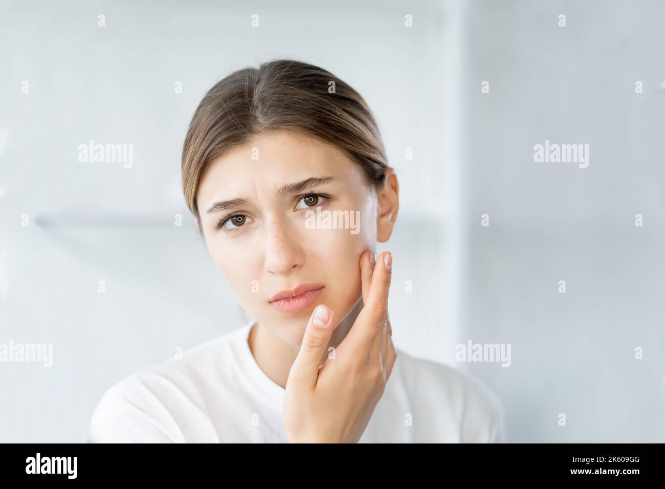 problema dell'acne infiammazione del viso donna che tocca la pelle Foto Stock
