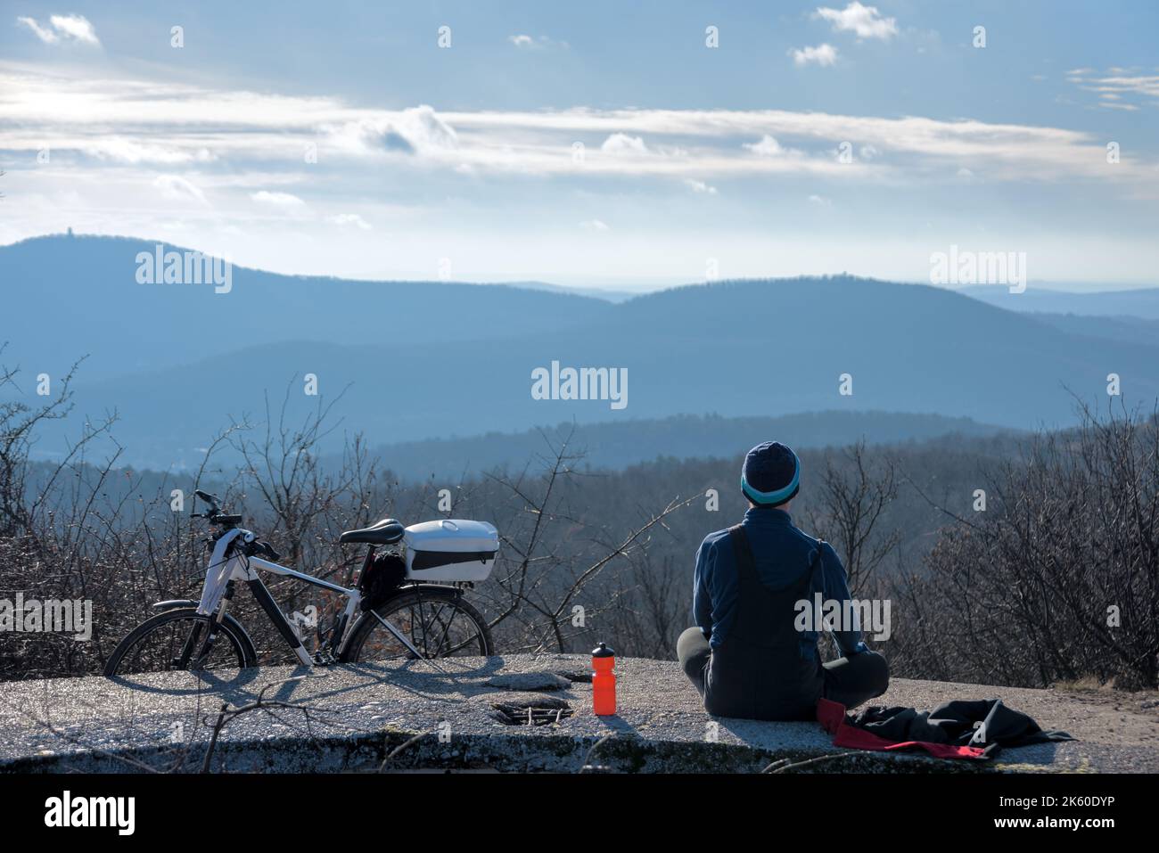 Persona seduta a guardare la vista della montagna con la bicicletta accanto a lui Foto Stock