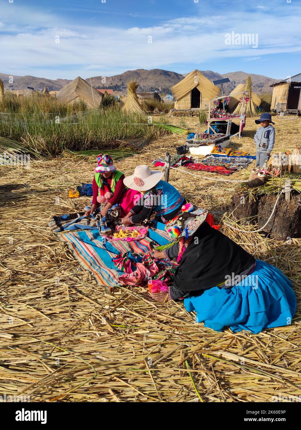 Donne degli Uru o Uros, indigeni del Perù e della Bolivia, mentre lavorano con pezzi di stoffa sulla loro isola galleggiante nel lago Titicaca. Foto Stock