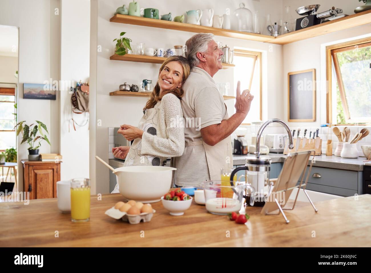 Coppia anziana danza, cucinare la colazione in cucina e l'amore per la preparazione del cibo insieme in tempo di pensione. Le persone anziane sorridono, si divertono a cucinare o a cucinare Foto Stock