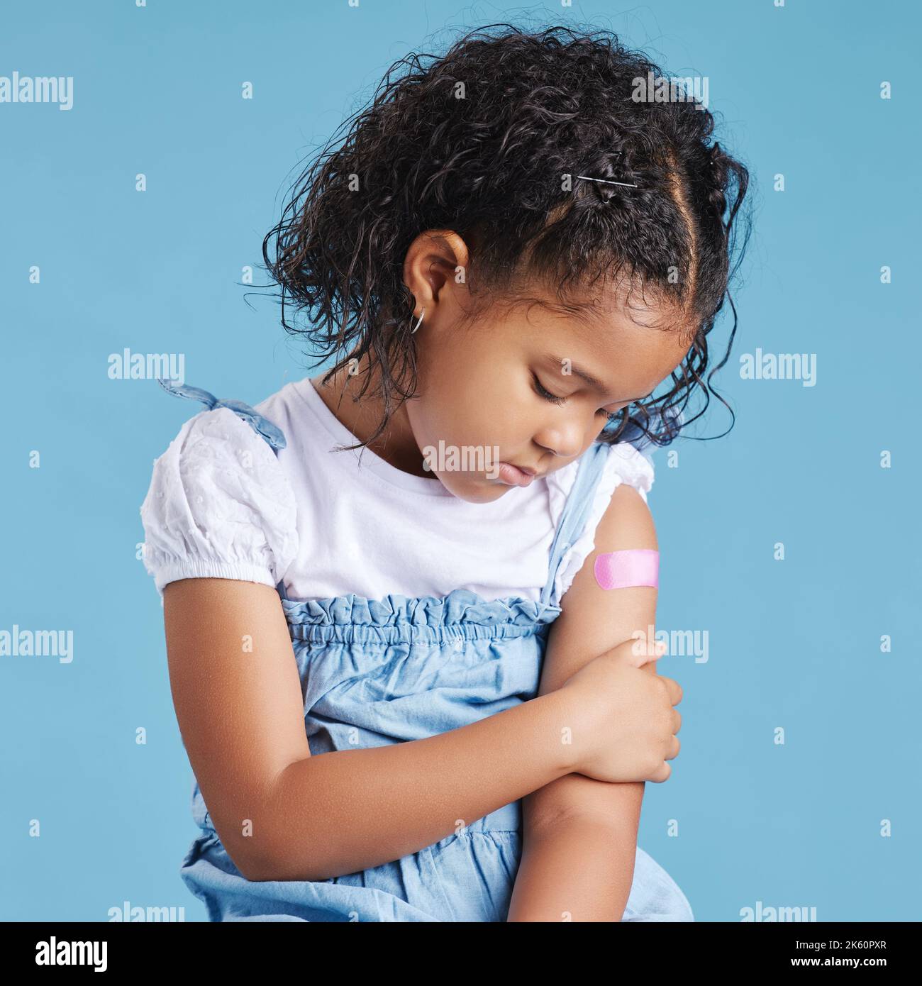 La bambina affetta, affetta, mostra un braccio vaccinato con bendaggio adesivo dopo essere stata iniettata con il vaccino Covid-19, motiva a vaccinare contro Foto Stock