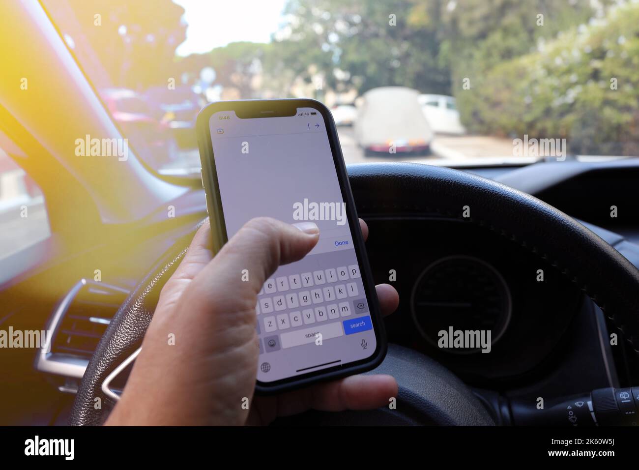 Invio di SMS durante la guida di un'auto. Scrivere e digitare il messaggio con il cellulare nel veicolo. Foto Stock