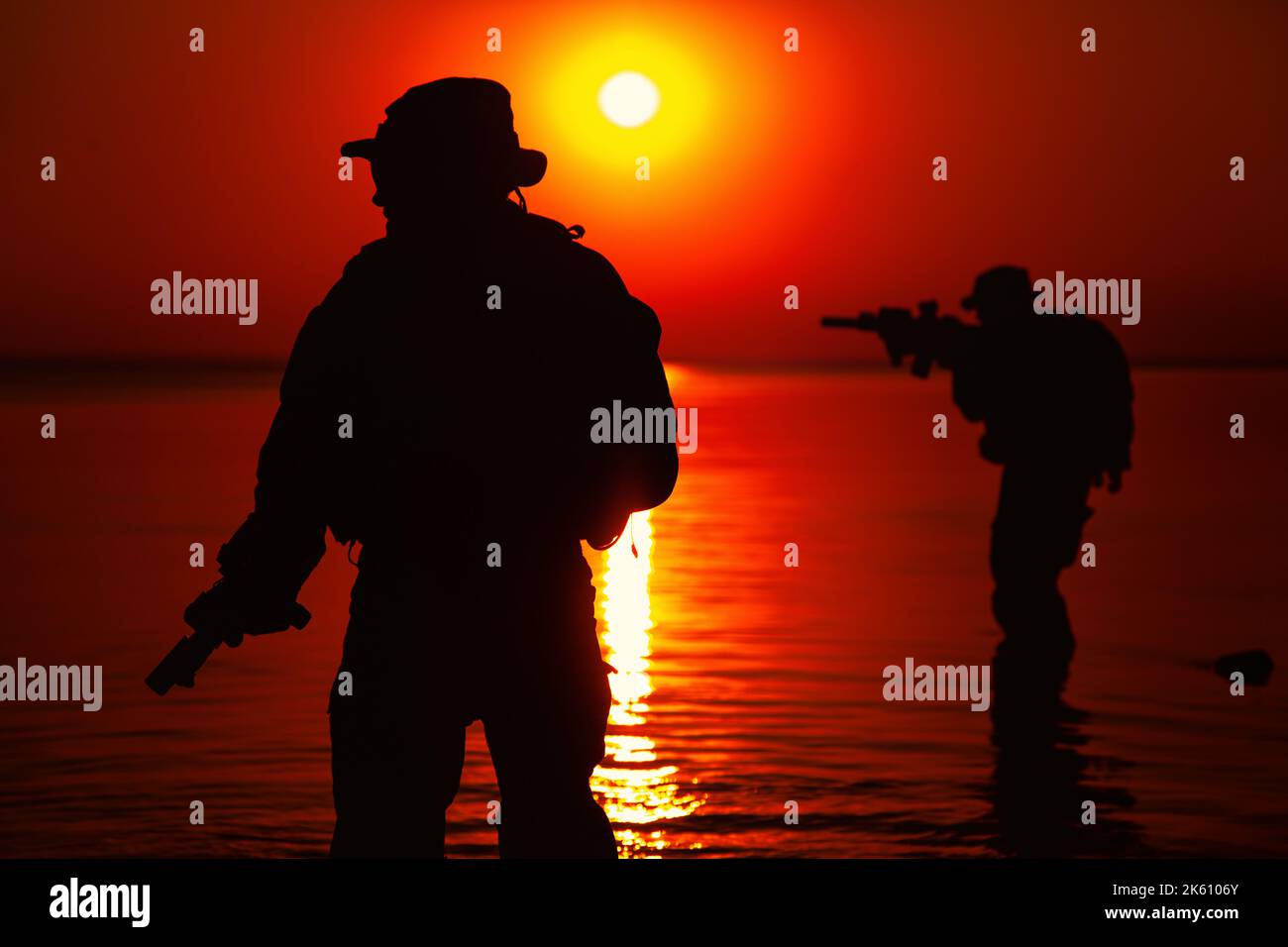 Soldati dell'esercito con fucili silhouette arancione tramonto in azione durante raid attraversando il fiume in acqua, due militanti con fucili Foto Stock