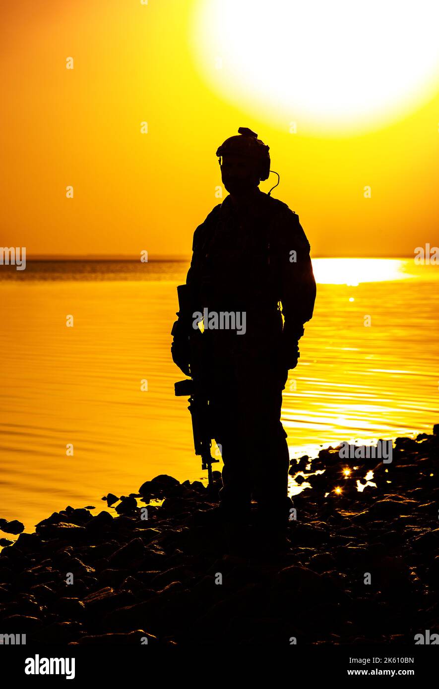Militare con fucile arancione silhouette tramonto Foto Stock